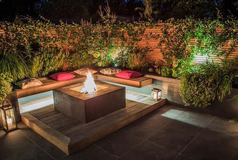 outdoor seating and heating area with outdoor lights illuminating the space